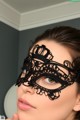 A woman wearing a black lace mask in a bathroom.