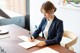 A woman sitting at a desk writing on a piece of paper.