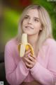 A young woman holding a banana in her hands.