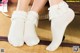 A pair of white socks with lace on them.