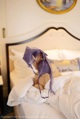 A woman laying on a bed holding a purple bra.