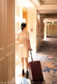 A woman walking down a hallway with a suitcase.