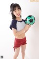 A young woman holding a soccer ball in her hands.