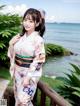 A woman in a kimono posing for a picture by the water.