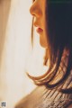 A woman looking out of a window with her hair blowing in the wind.