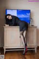 A woman leaning on a cabinet in front of a television.