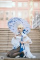 A woman in a white dress holding an umbrella.