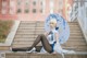 A woman sitting on the steps of a building holding an umbrella.