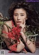 A woman laying on the ground holding a bunch of red flowers.