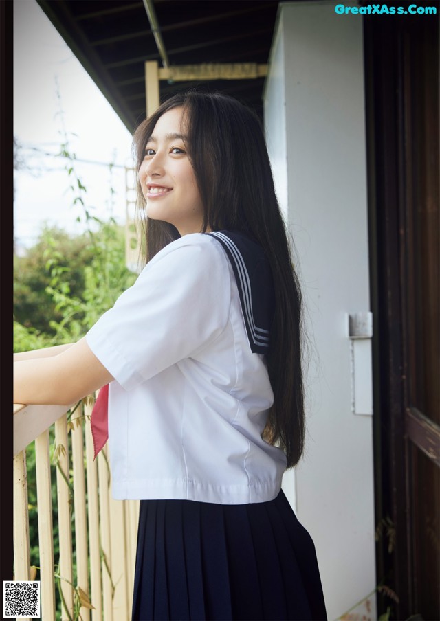 A woman in a school uniform leaning against a railing.