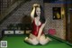 A woman in a red bathing suit sitting on a pool table.