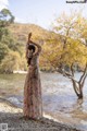 A woman in a long dress standing in the water.