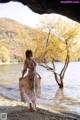 A woman in a long dress standing in the water.