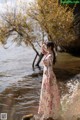 A woman in a long dress standing in the water.