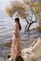 A woman standing on a rock by the water.