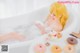 A woman sitting in a bathtub with donuts on a plate.