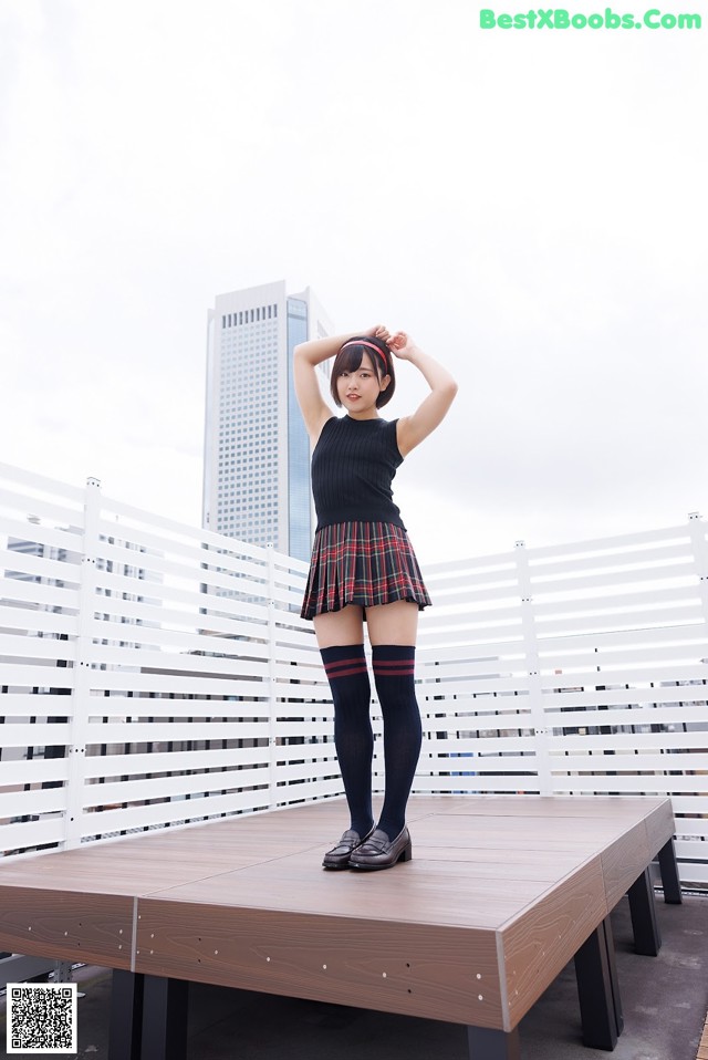 A woman in a school uniform standing on a wooden platform.