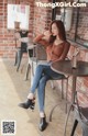 a woman sitting at a table in front of a brick wall