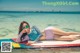 A woman laying on a surfboard in the ocean.