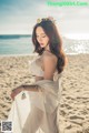 A woman in a white dress standing on a beach.