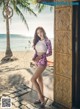 A woman standing on a beach next to a palm tree.