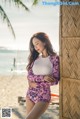 A woman in a bathing suit leaning against a wall on the beach.