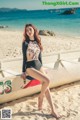 A woman sitting on top of a boat on a beach.