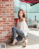 A woman sitting on a red chair in front of a brick wall.