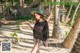 A woman in a black dress and hat walking on a beach.