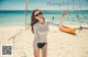 A woman standing on a beach next to a volleyball net.