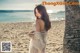 A woman standing on a beach next to a palm tree.