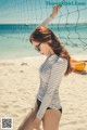 A woman in a bikini standing next to a volleyball net.