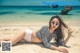 A woman laying on a sandy beach next to the ocean.