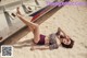 A woman laying on the sand next to a boat.