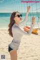 A woman standing on a beach next to a volleyball net.