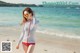 A woman in a striped shirt and red bikini on the beach.