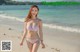 A woman in a bikini walking on a beach.