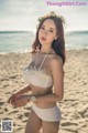 A woman in a white bikini standing on a beach.