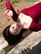 A woman in a red dress laying on a wooden bench.