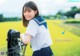 A woman in a school uniform standing next to a bicycle.