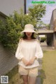 A woman wearing a white top and beige shorts.