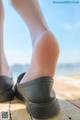 A person wearing a pair of black shoes on a wooden dock.