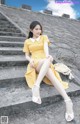 A woman in a yellow dress sitting on some steps.