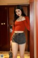 A woman in a red top and black shorts posing for a picture.