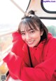 A woman in a red hoodie smiles at the camera.