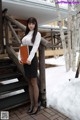 A woman in a white shirt and black skirt holding a book.