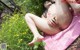 A woman laying on a pink towel in the grass.