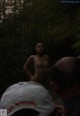 A naked woman standing in the middle of a forest.