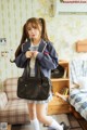 A young woman in a school uniform holding a black bag.